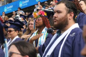 A group of graduates in blue caps and gowns standing for performances of The Star-Spangled Banner and Lift Every Voice and Sing at the 皇冠app 2025 commencement ceremony.