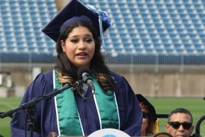 A close-up of Goodwin's graduate Jayanna E. Rodriguez delivering her speech on stage at the podium.