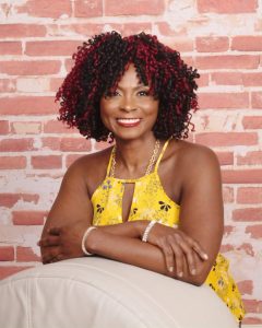 Susan Johnson smiles at the camera against a brick background