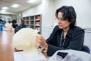 A 葬礼 student practices facial reconstruction techniques at 皇冠app.