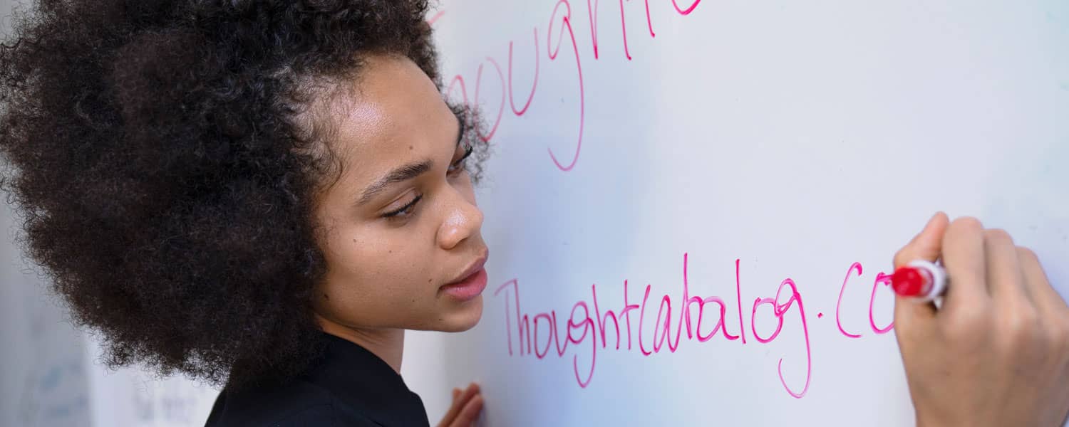 M.Ed. student writing on a whiteboard