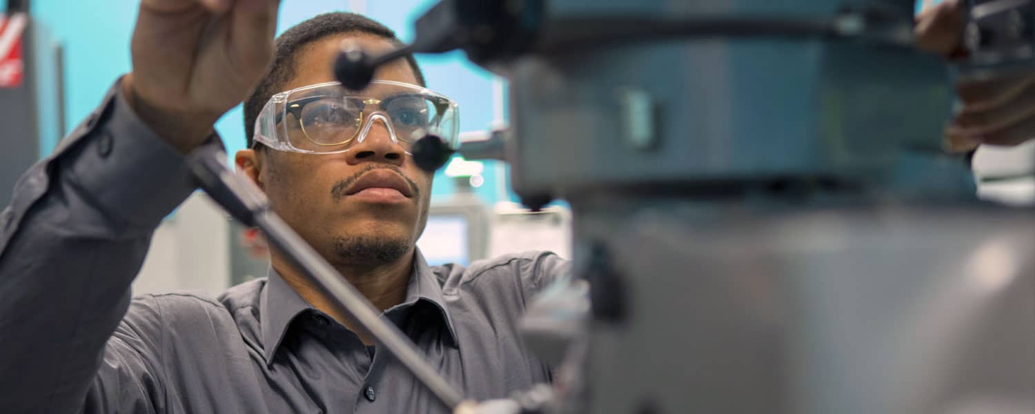 student adjusting manufacturing equipment